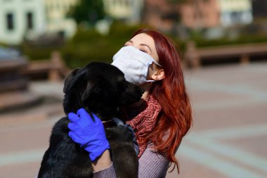 Genç bir kadın, köpeğiyle dolaşmayı önlemek için yüz maskesi kullanıyor. Global COVID-19 salgın hastalık konsepti, hayvanlar