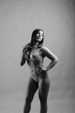 Stüdyoda güzel, seksi, tombul bir kadın. Stüdyo resmi, mavi arka planda pembe iç çamaşırı.