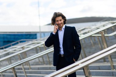 Yakışıklı bir işadamının portresi telefon ve kahve fincanı şehir sokaklarında.