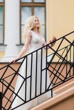 Minsk, Belarus - 05.05.2020. Parkta yürüyen ve gülümseyen kıvırcık saçlı sarışın gelin, konsept düğün.