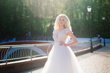 Minsk, Belarus - 05.05.2020. Parkta yürüyen ve gülümseyen kıvırcık saçlı sarışın gelin, konsept düğün.