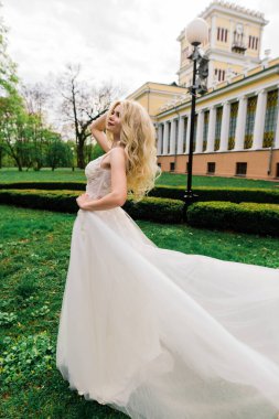 Minsk, Belarus - 05.05.2020. Parkta yürüyen ve gülümseyen kıvırcık saçlı sarışın gelin, konsept düğün.