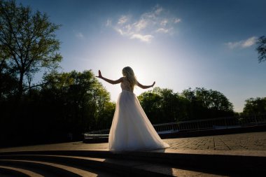 Minsk, Belarus - 05.05.2020. Parkta yürüyen ve gülümseyen kıvırcık saçlı sarışın gelin, konsept düğün.