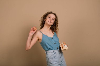 Stüdyoda elinde yumurta tutan kıvırcık bir kadın var. Gri arka planda fotokopi odası. Duygusal Portre