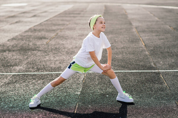 Girl jogging on a sunny summer evening, laying on treadmill, stadium, physical training, back to school, tired.