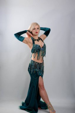 Genç, güzel, egzotik doğu kadınları etnik yeşil elbiseler içinde göbek dansı yapıyorlar. Beyaz arka planda izole edilmiş. Stüdyo çekimi