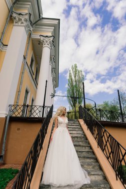 Parkta yürüyen ve gülümseyen kıvırcık saçlı sarışın gelin, konsept düğün.