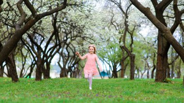 Bahçenin çiçeklerinde gülümseyen ve oynayan güzel bir kız çocuğu, çiçek açan ağaçlar, kiraz..