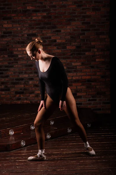 芭蕾舞演员穿着深色的紧身衣穿着深色的内衣裤砖墙 木制楼层 — 图库照片