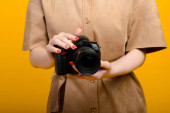 Obrázek rukou s digitální fotoaparát na žlutém pozadí