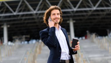 Yakışıklı bir işadamının portresi telefon ve kahve fincanı şehir sokaklarında.