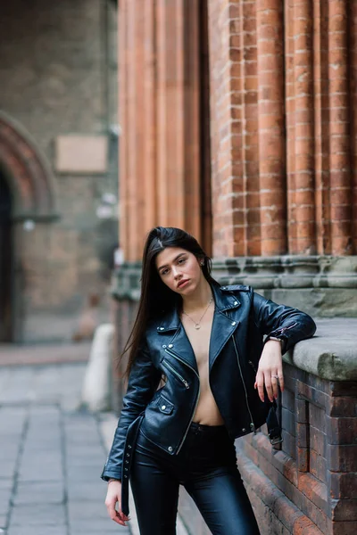 Portrait of beautiful young brunette woman wearing stylish black leather jacket, she smiling on urban background, happy time, Travel Concept.