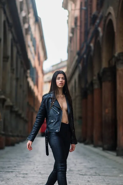 スタイリッシュな黒の革のジャケットを身に着けている美しい若いブルネットの女性の肖像画 彼女は都会の背景 幸せな時間 旅行コンセプトに笑みを浮かべて — ストック写真