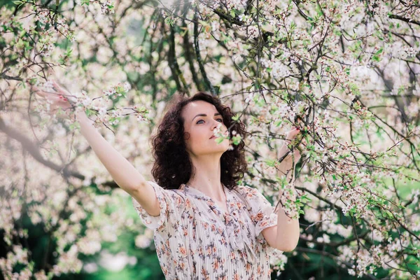 Bahar Çiçekli Bahçede Poz Veren Kıvırcık Saçlı Çekici Bir Kadın — Stok fotoğraf