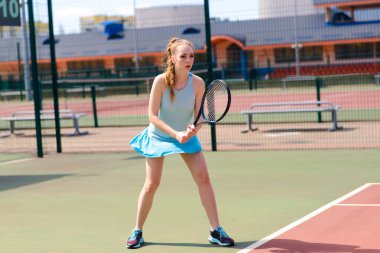 Sahada tenis raketi tutan beyaz elbiseli ve topuklu ayakkabılı seksi kız tenisçi. Genç kadın tenis oynuyor.