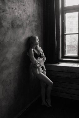 Siyah iç çamaşırlarıyla poz veren seksi sarışın ve stüdyoda beyaz gömlekli.