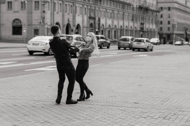 Korumacı tıbbi maske takmış genç bir çift sokakta yüz yüze. Virüs koruması altında bir adam ve kız..