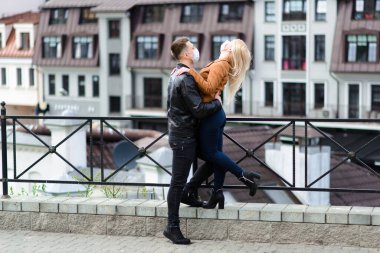 Korumacı tıbbi maske takmış genç bir çift sokakta yüz yüze. Virüs koruması altında bir adam ve kız..