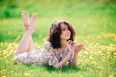 Bahar çiçekli bahçede poz veren kıvırcık saçlı çekici bir kadın.