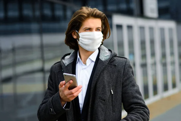 Young man in a medical mask outside, no money, poverty, hardship. Quarantine, isolation.