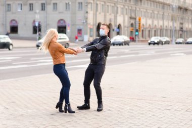 Korumacı tıbbi maske takmış genç bir çift sokakta yüz yüze. Virüs koruması altında bir adam ve kız..