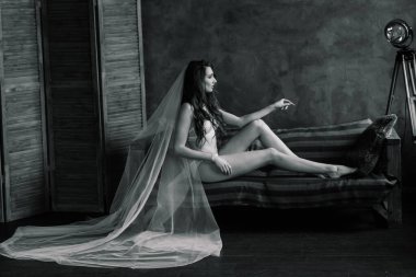 Gelinin sabahı. Beyaz dantel iç çamaşırıyla poz veren seksi kız. Beyaz iç çamaşırlı güzel bir kadının portresi. Beyaz çarşaflı baştan çıkarıcı kadın ve bir peignoir..