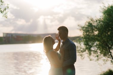 Birbirine aşık çiftler, turuncu gün batımında gölün arkasında hafif bir siluet. Romantik..