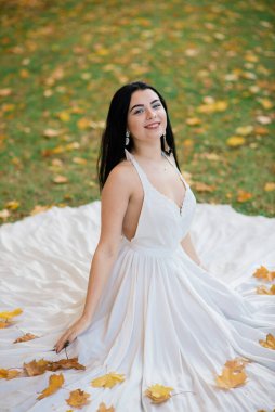 Güz parkında beyaz elbiseli güzel esmer bir kadın.