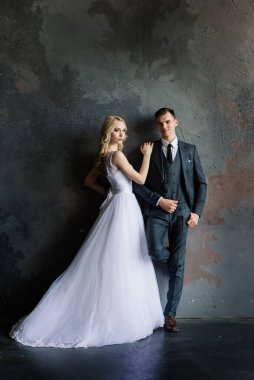 Klasik bir stüdyonun içinde şirin bir düğün çifti. Öpüşüyorlar ve sarılıyorlar..