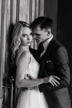 Klasik bir stüdyonun içinde şirin bir düğün çifti. Öpüşüyorlar ve sarılıyorlar..