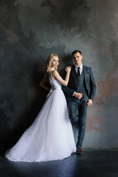 Klasik bir stüdyonun içinde şirin bir düğün çifti. Öpüşüyorlar ve sarılıyorlar..