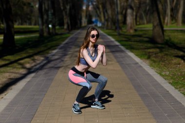 Spor kıyafetleri ve gözlükleriyle parkta güzel bir atletik kız. Sağlıklı bir yaşam tarzı. Yumuşak seçici odak.
