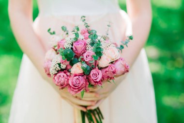 Gelinin ellerinde bir buket beyaz ve kırmızı gül, park