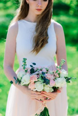 Gelinin ellerinde bir buket beyaz ve kırmızı gül, park