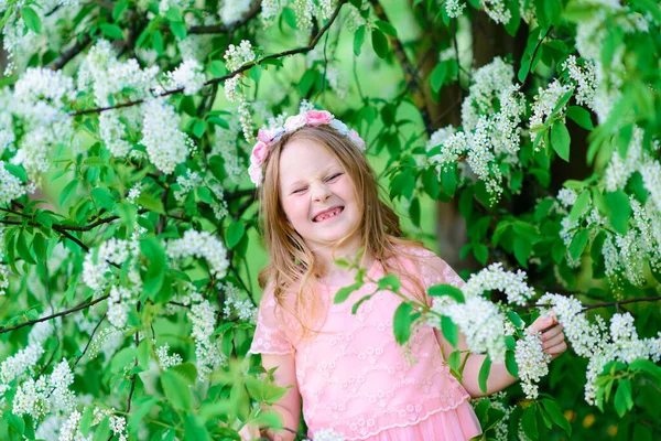Bahçenin çiçeklerinde gülümseyen ve oynayan güzel bir kız çocuğu, çiçek açan ağaçlar, kiraz..