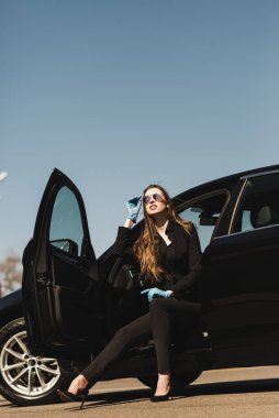 Siyah elbiseli, pahalı arabalı genç bir iş kadını.