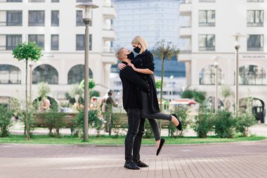 Coronavirus salgını karantinası sırasında Avrupa şehrinin boş sokaklarında gezen modaya uygun koruyucu maskeler, kot ceketler giyen çift.