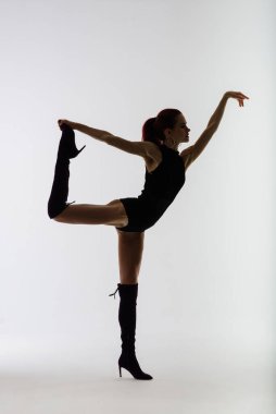 Siyah tulumlu, esnek, genç ve güzel bir kadın dans stüdyosunda poz veriyor..
