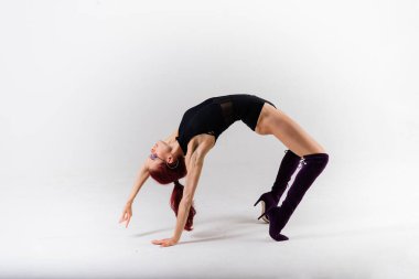 Siyah tulumlu, esnek, genç ve güzel bir kadın dans stüdyosunda poz veriyor..