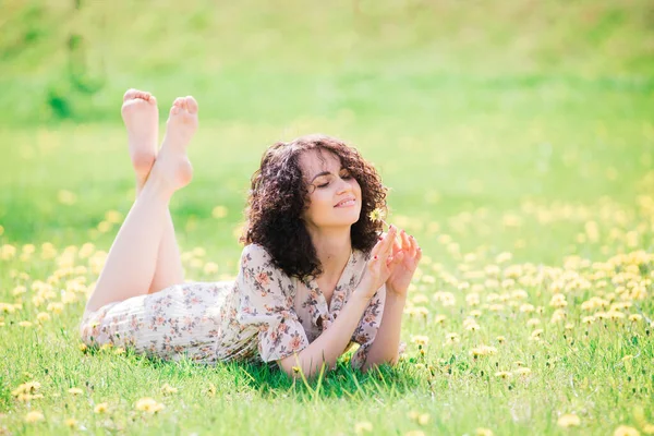 Bahar çiçekli bahçede poz veren kıvırcık saçlı çekici bir kadın.