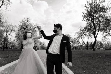 Düğün günlerinde karantina sırasında parkta maske takan genç bir çift..