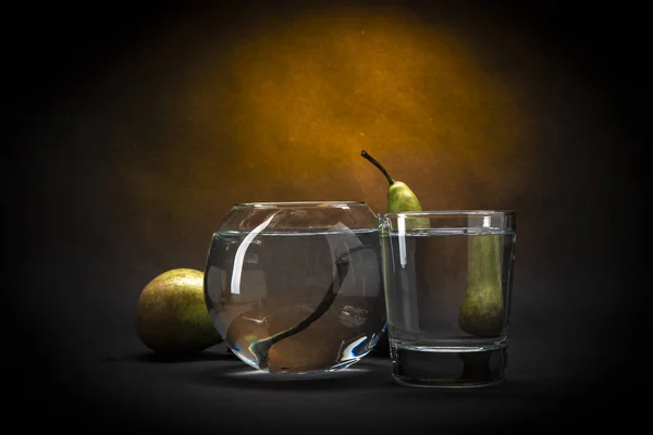 ガラス容器の中の水の暗い背景に静物梨 — ストック写真
