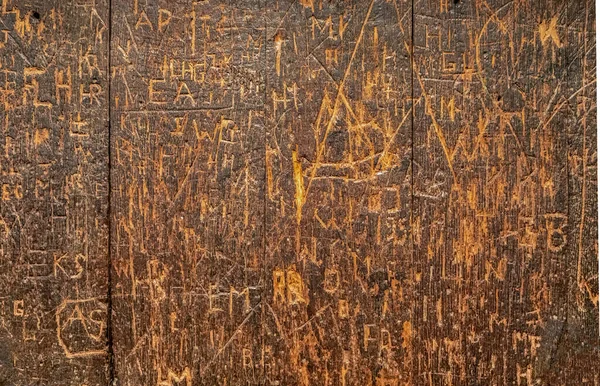 Alte Holzoberfläche Mit Vielen Gravierten Graffiti Tags Überzogen — Stockfoto