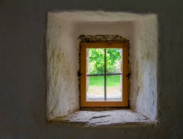 sunny scenery seen through a historic window in a thick wall