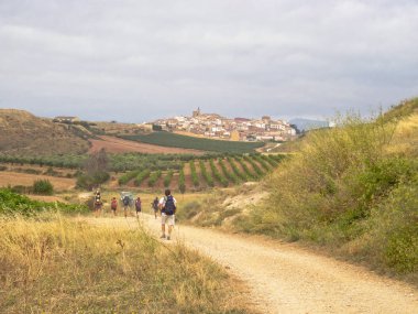 Pilgrims walk from Maneru to the medieval hilltop village Cirauqui - Navarre, Spain, 6 September 2014 clipart