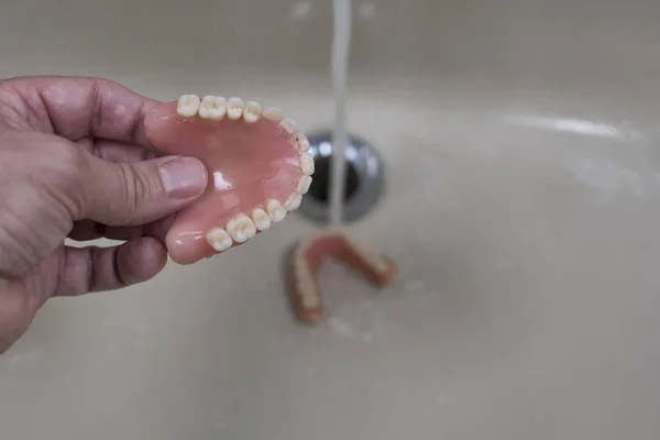 denture cleaning in the sink with running water