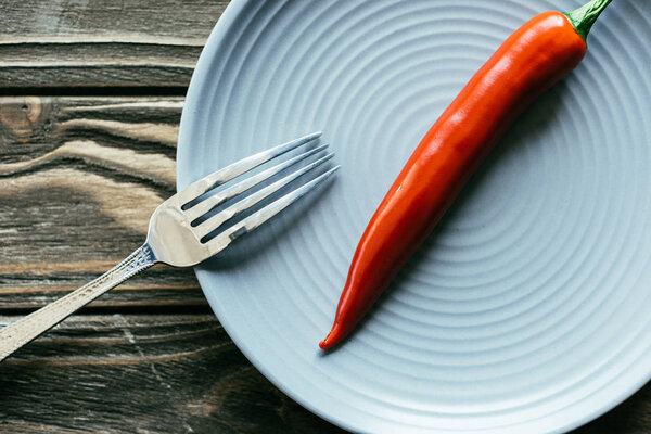 Blue plate with spicy pepper on wooden table