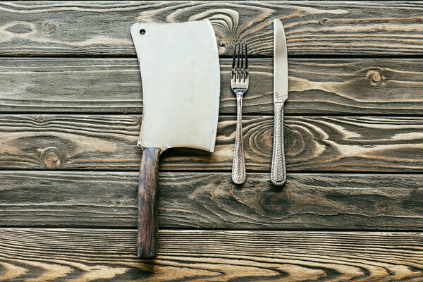 Silverware set and cleaver on wooden table