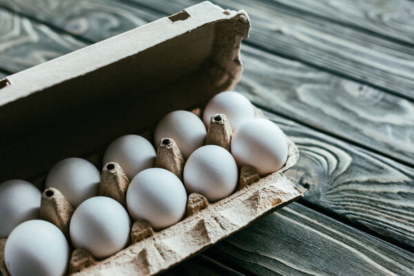 Carton box with white eggs on wooden table