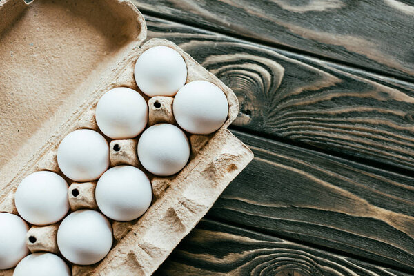 Carton container with chicken eggs on wooden table